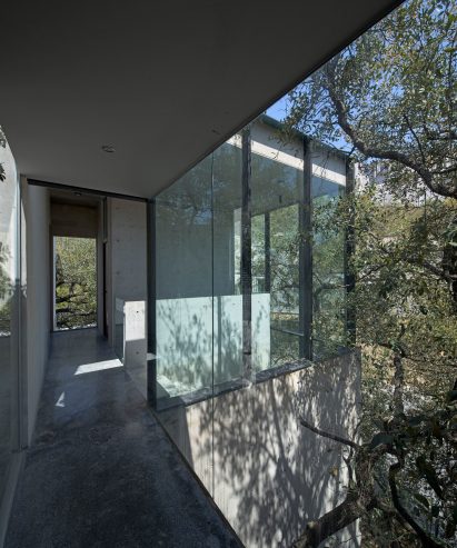 A corridor in a house next to floor-to-ciling-windows