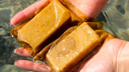 A pair of hands holding soap in beige packaging