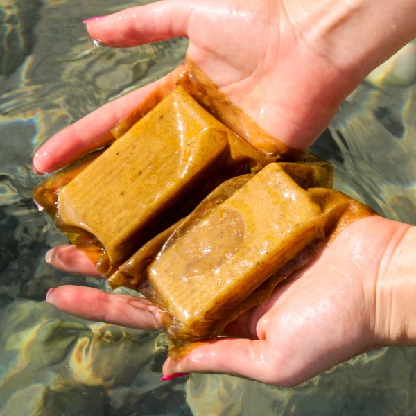 A pair of hands holding soap in beige packaging