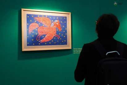 Person standing in front of a painting by Maria Prymachenko