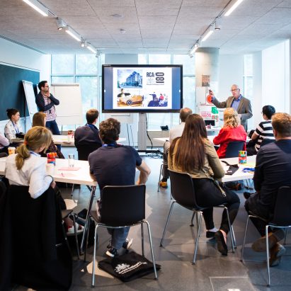 People in a class room looking towards a digital screen