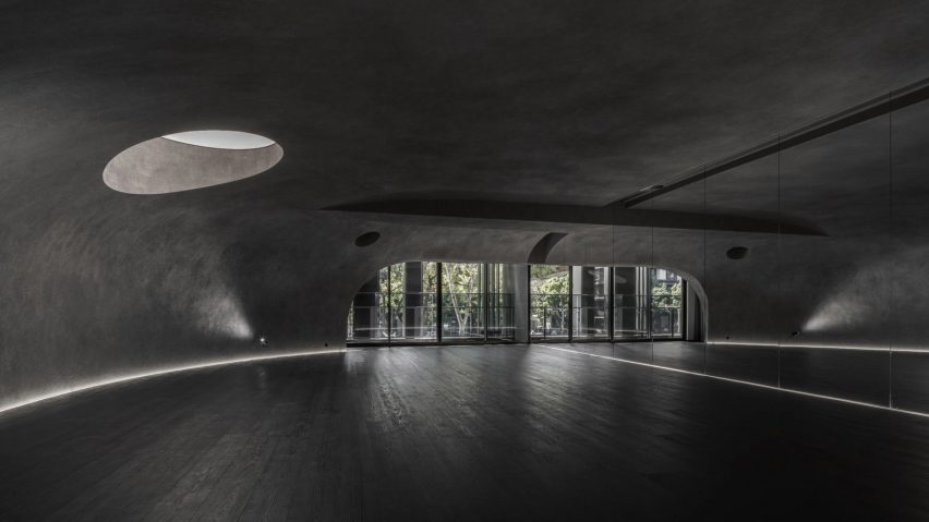 Large wood-floored yoga stusio with curvilinear walls and ceiling