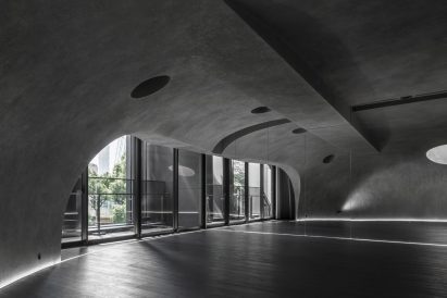 Large wood-floored yoga stusio with curvilinear walls and ceiling