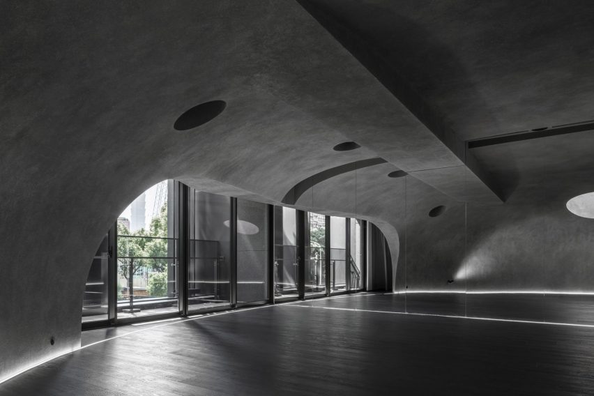 Large wood-floored yoga stusio with curvilinear walls and ceiling