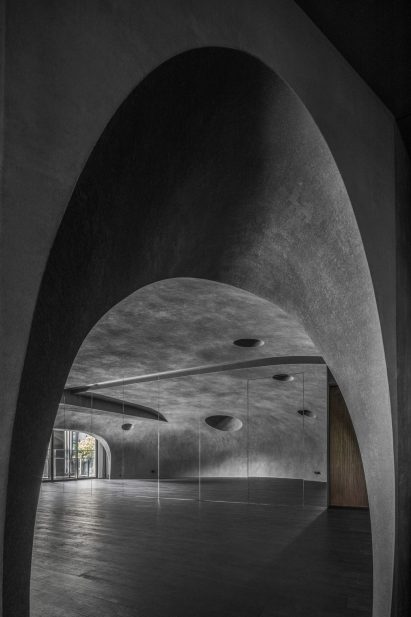 Large wood-floored yoga stusio with curvilinear walls and ceiling