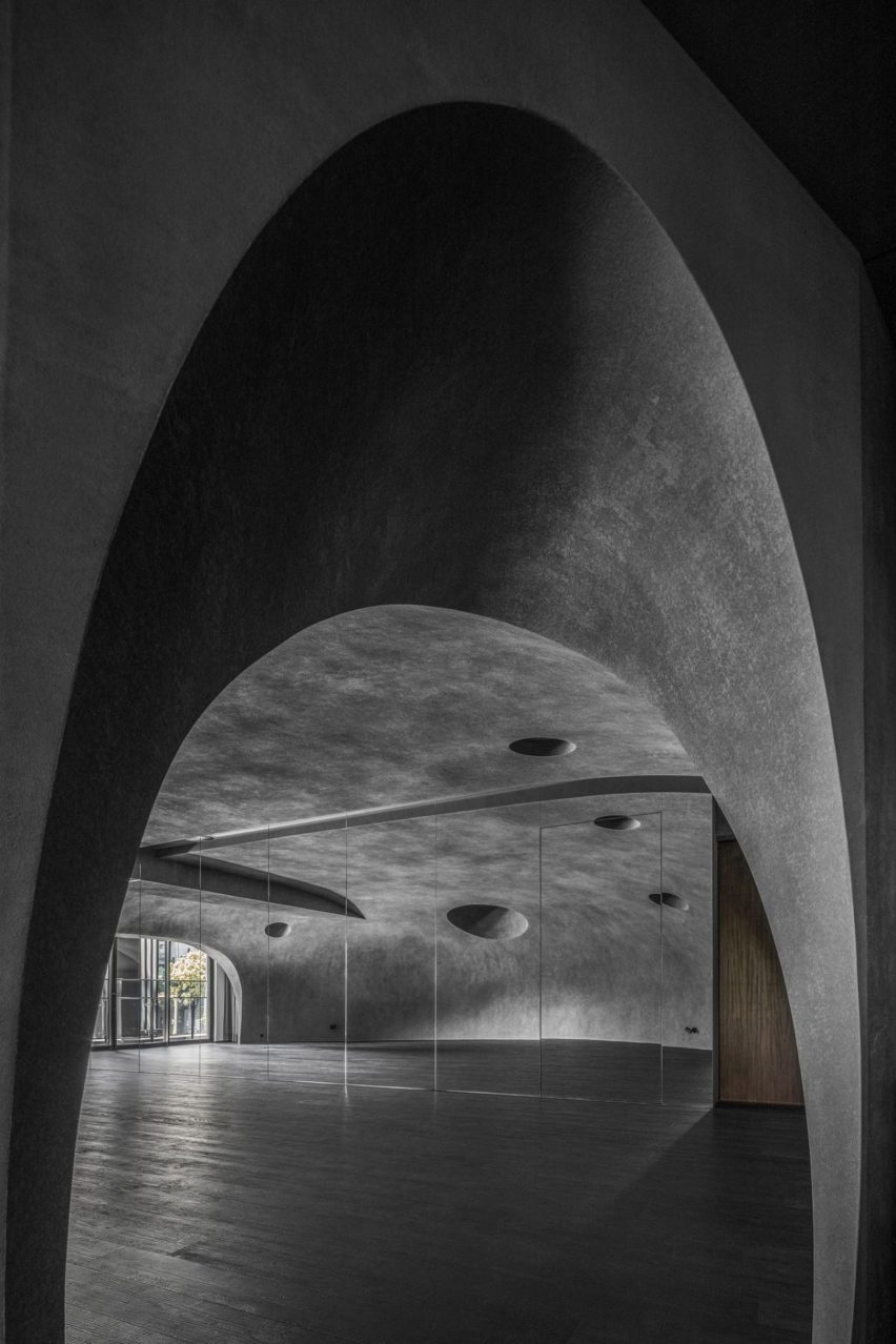 Large wood-floored yoga stusio with curvilinear walls and ceiling