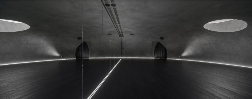 Large wood-floored yoga stusio with curvilinear walls and ceiling