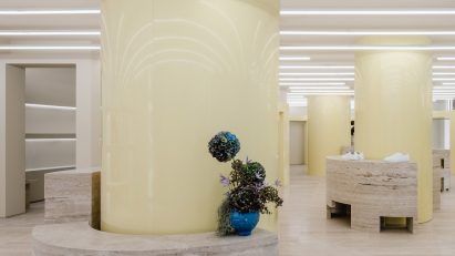 Glossy butter yellow columns and travertine plinths in Axel Arigato's Berlin store
