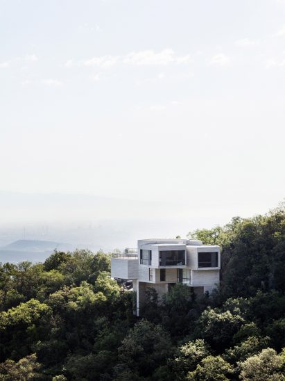 Casa Ventura emerging from a forested hillside 