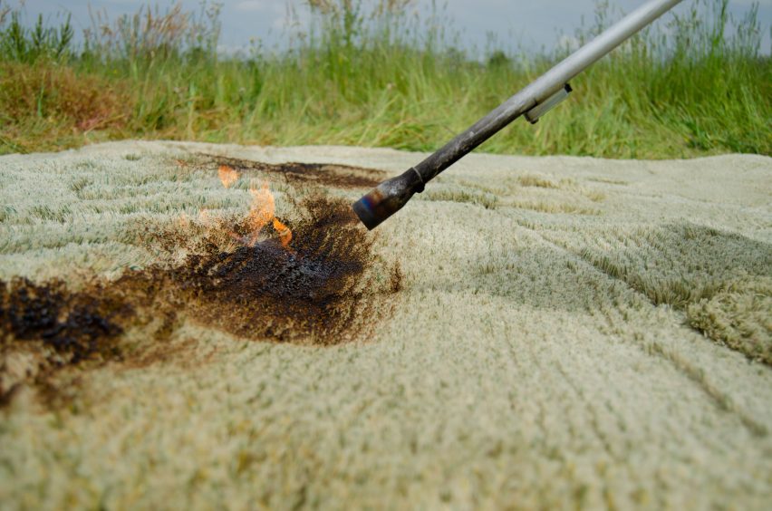 Close-up of flame thrower burning the fibres of a grassy rug outdoors in a meadow
