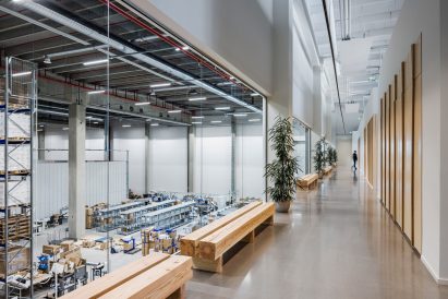 Photo showing views of a warehouse floor through large windows in an office corridor