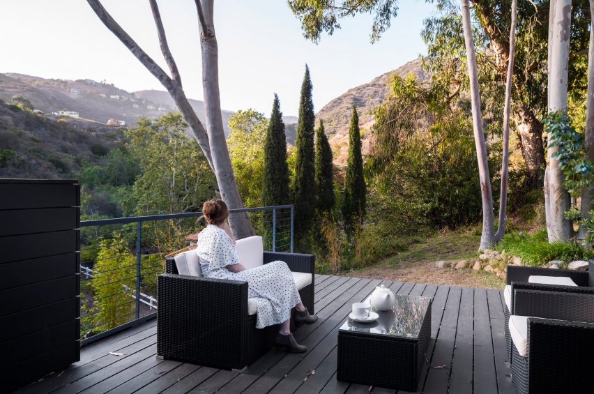 A woman sitting on a patio overlooking mountains