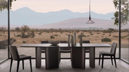 Dining table in front of large glass windows looking out over a remote landscape