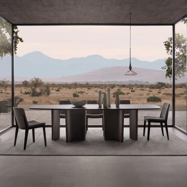 Dining table in front of large glass windows looking out over a remote landscape