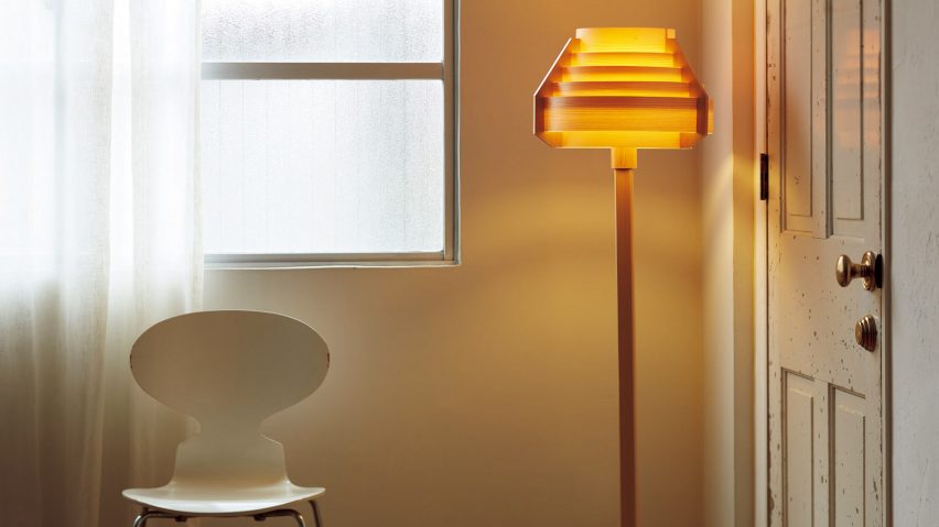 Orange glowing standing lamp beside door and chair