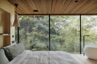 Bed with white cover in front of forest