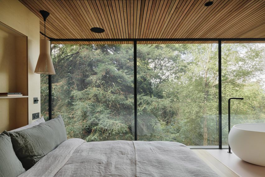 Bed with white cover in front of forest