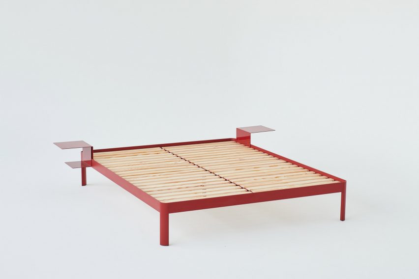 Photograph of a red bed frame with two side tables in a white background