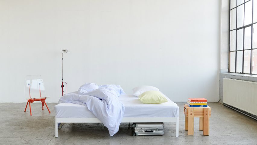 Photograph of a white bed in a white room with big glass windows