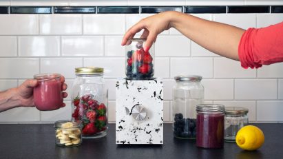 Person using the Re:Mix blender with various fruits