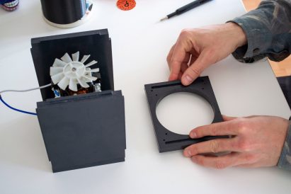 A person plays with the disassembled parts of a kitchen mixer at a table