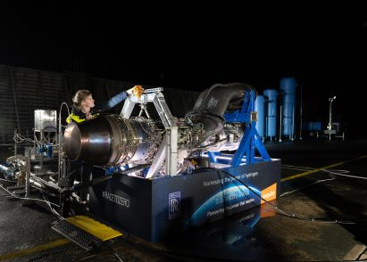 Photo of a woman in hi-vis adjusting parts on a large aircraft engine