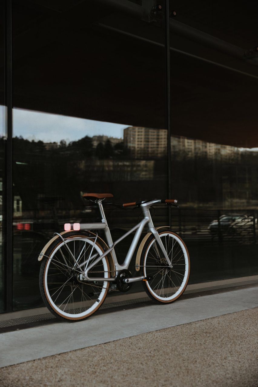Photograph of a grey electronic bike in front of a glass window