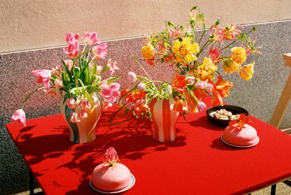 Red table with colourful vases filled with flowers