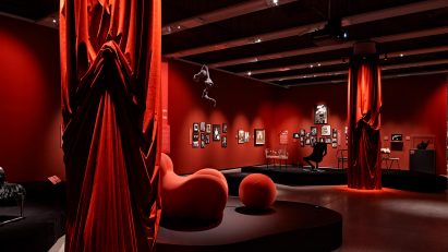 Chairs, sofas, red curtains and other objects displayed within the exhibition