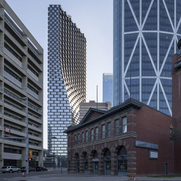 Curving tower in view behind traditional low brick building