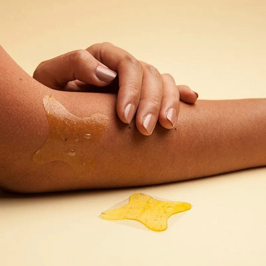 Hand smoothing patch onto arm on yellow background