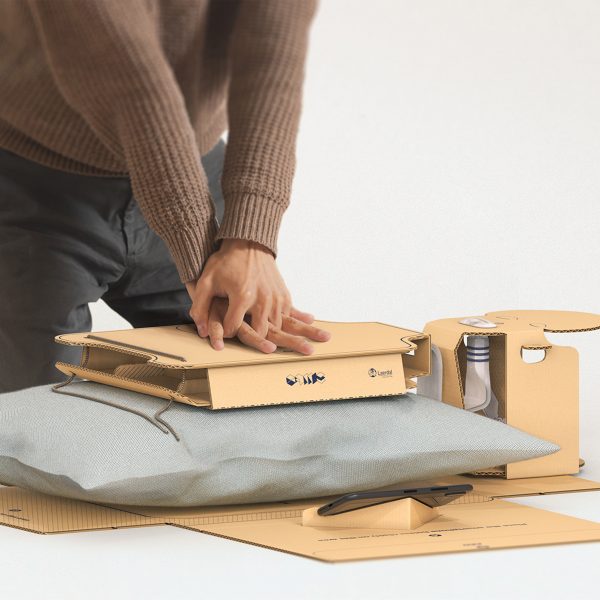 Person pressing down on cardboard packaging and a pillow