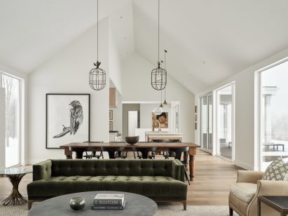 Gabled all-white interior with green sofa and cage lamps