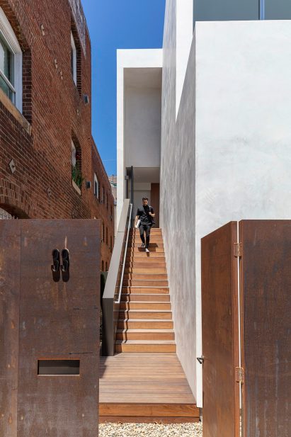 Wooden entry stair on stucco house by EYRC