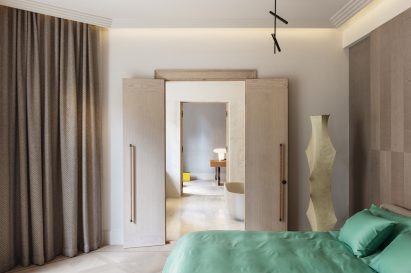 Bedroom with green bed and sculptural lamp