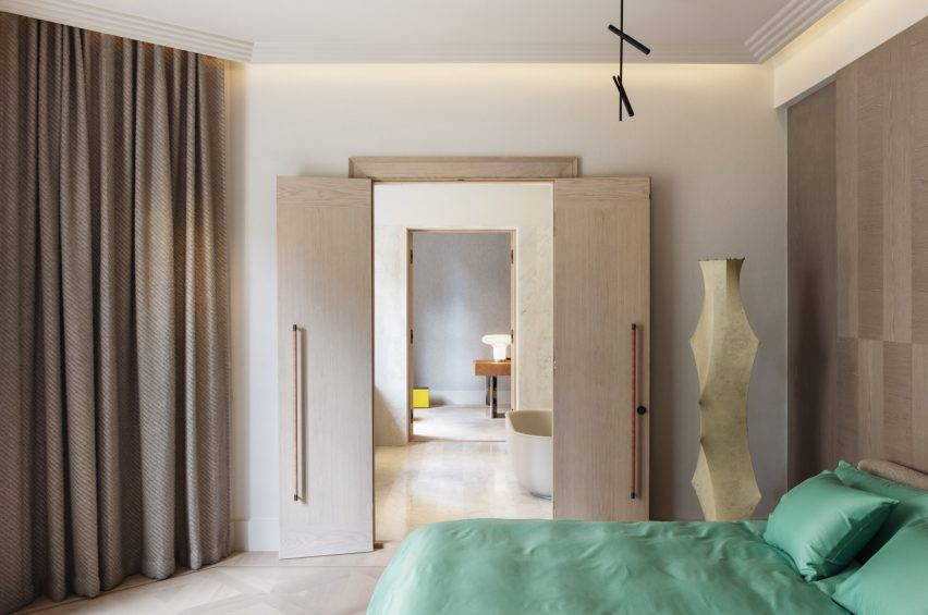 Bedroom with green bed and sculptural lamp