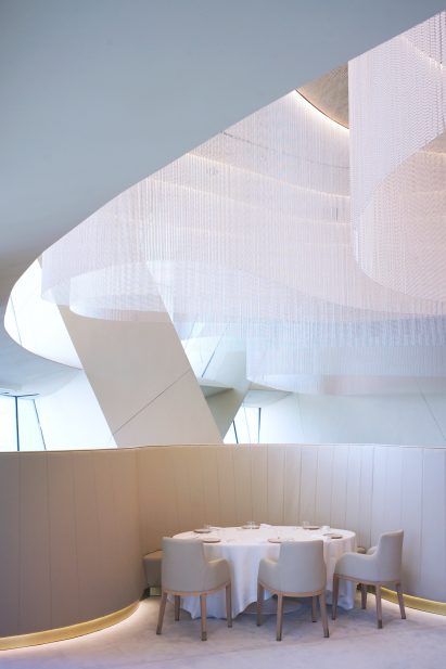 Restaurant table and chairs underneath sculptural ceiling