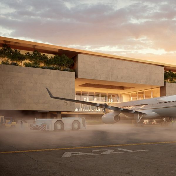 Airplane parked at a terminal clad in beige stone with greenery