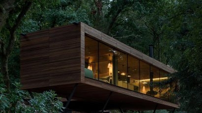 Timber cabin in woodland at dusk