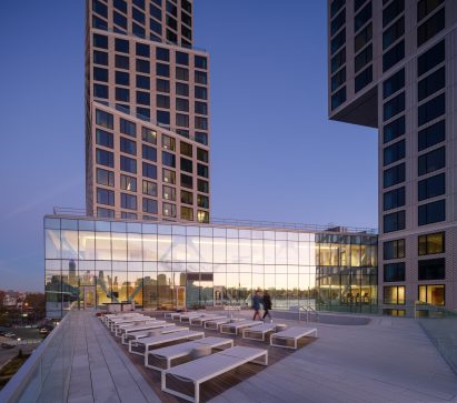 Glass bridge with swimming pool deck and tower in background