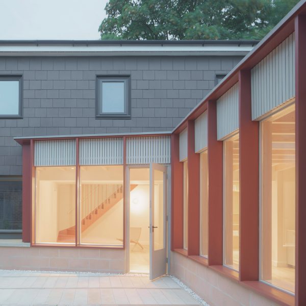Grey house facade with red timber extension