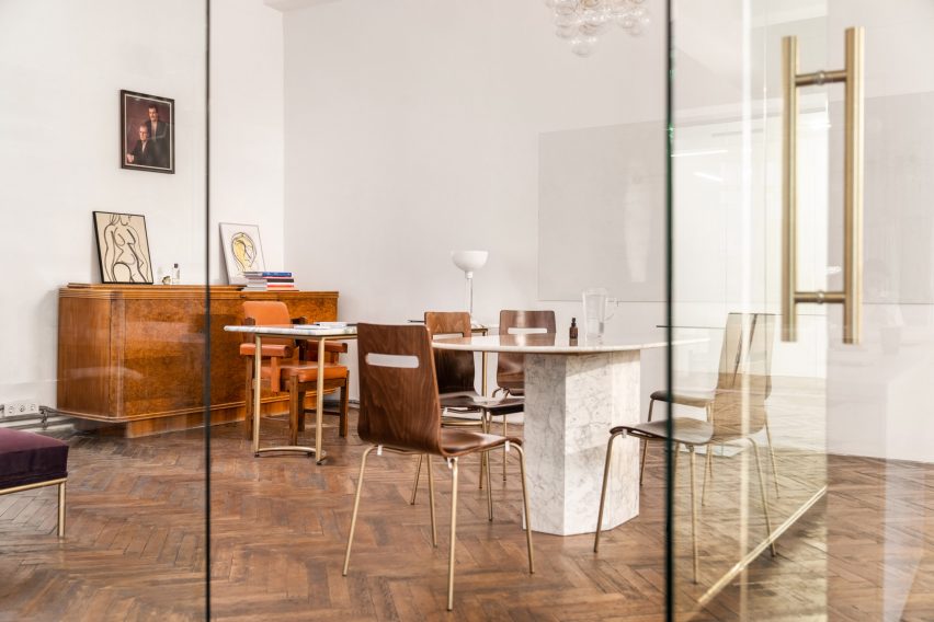 Photograph through glass wall of mismatched chairs around a table