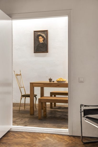 Photograph through doorway of mismatched chairs around a table
