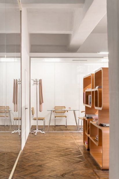Photograph showing corridor with parquet floor and rounded-edged book shelf