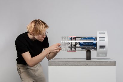 Photograph of person tinkering with a device on a plinth