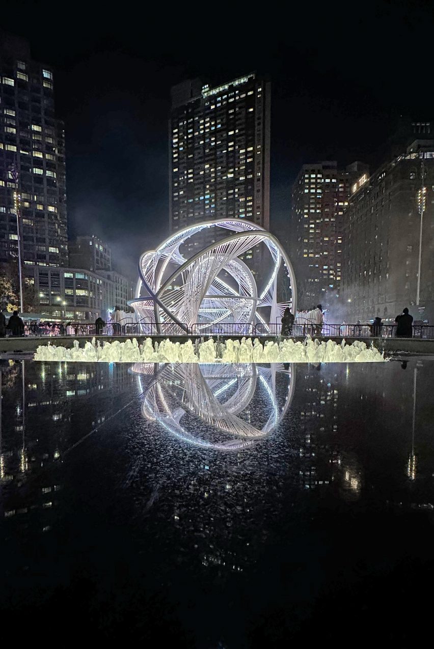 An arched sculpture reflected in water
