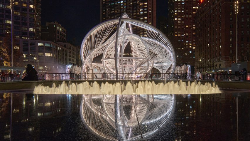 Your Voices installation lit up at night in front of a water fountain