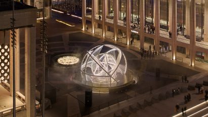 An aerial view of an arched sculpture in a plaza