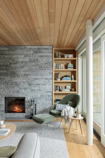 Fireplace against flat stone wall in main living room of house by BattersbyHowat