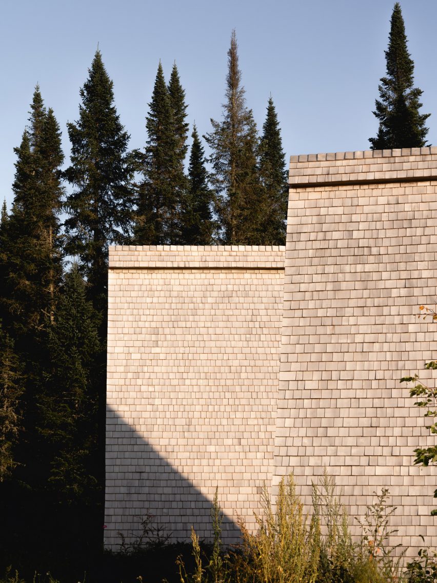 Two steep-pitched roofs clad in cedar shingles in a forest
